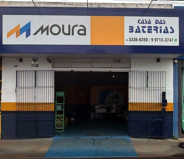 Fachada da Casa das Baterias, com o letreiro da Moura e da loja, a faixa amarela e o barrado azul